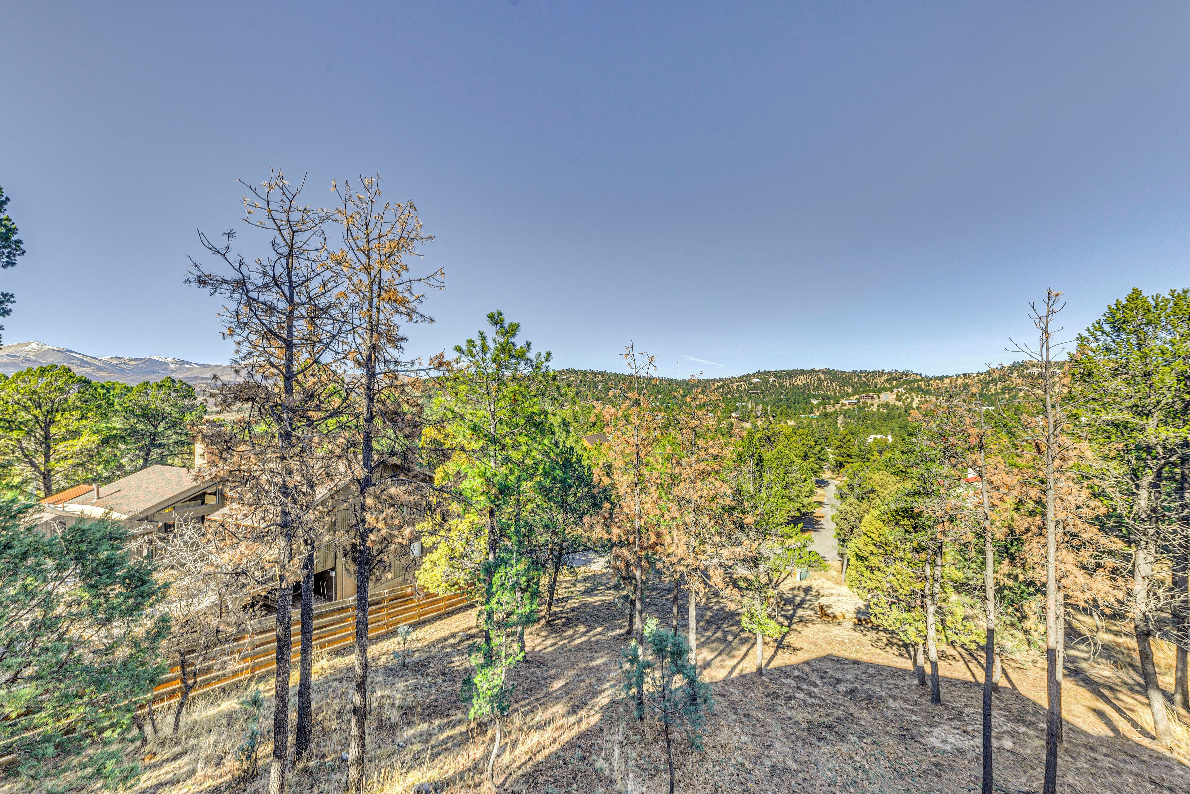 A mountainous landscape with a clear sky, a train track, and sparse vegetation.