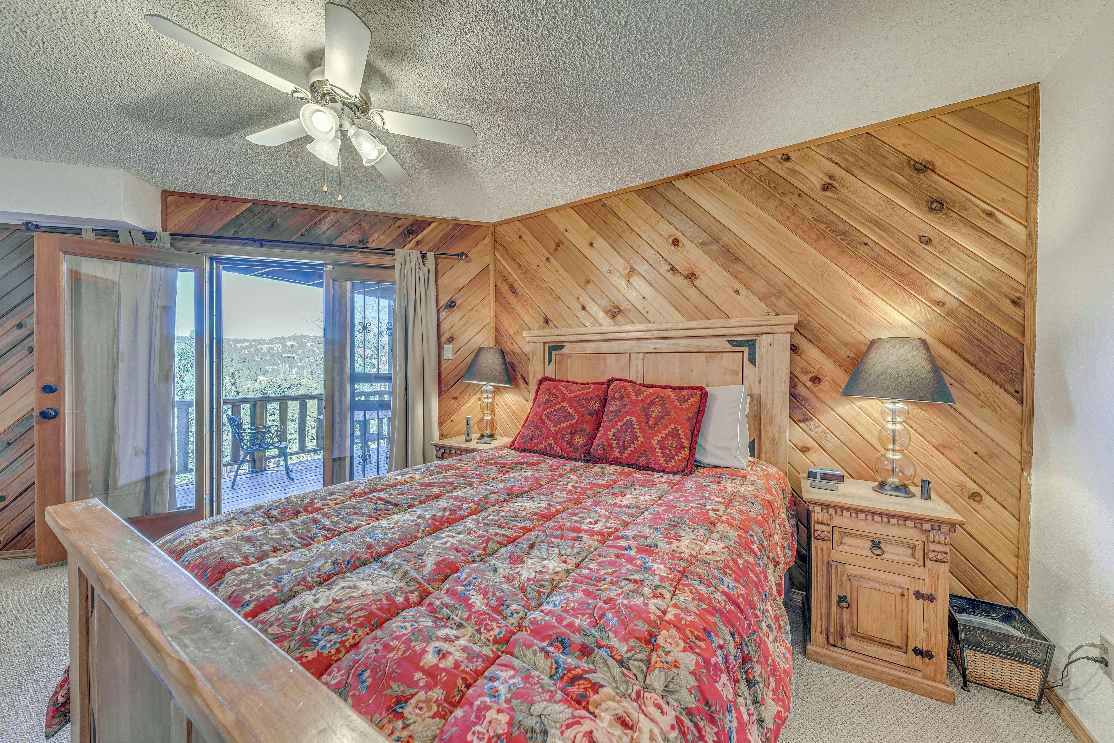 A bedroom with a wooden ceiling, a bed with a floral bedspread, two bedside lamps, and a nightstand with drawers.