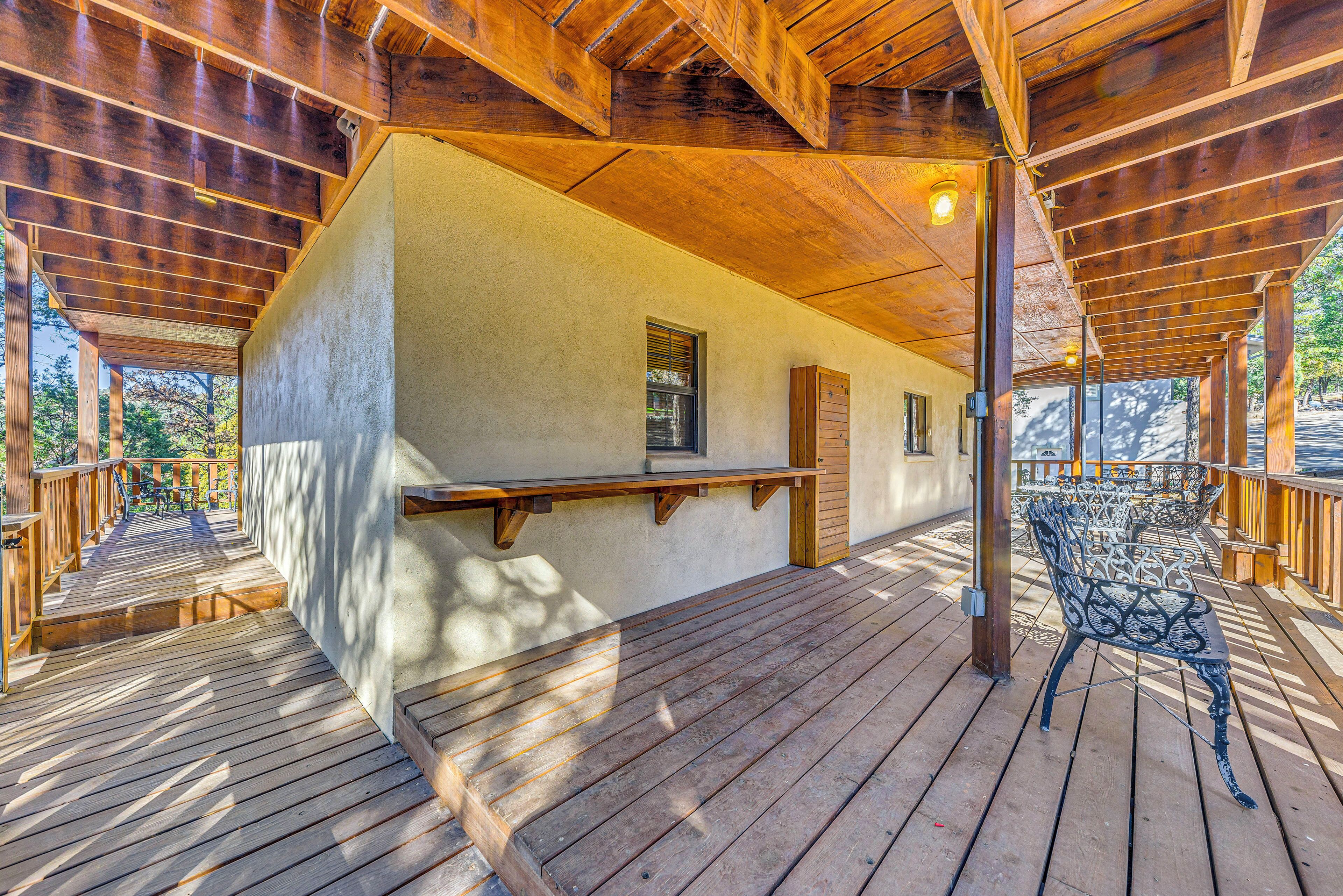 A wooden deck with a bench and a table, surrounded by a wooden railing.