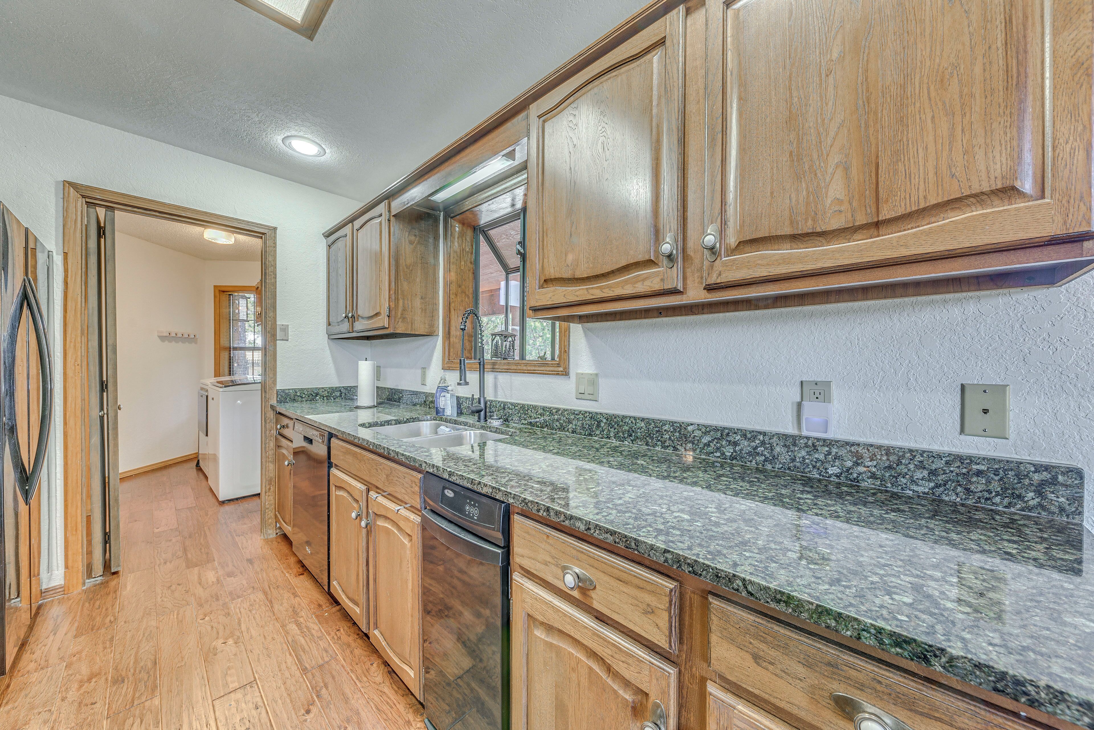 A kitchen with wooden cabinets, granite countertops, and a dishwasher.