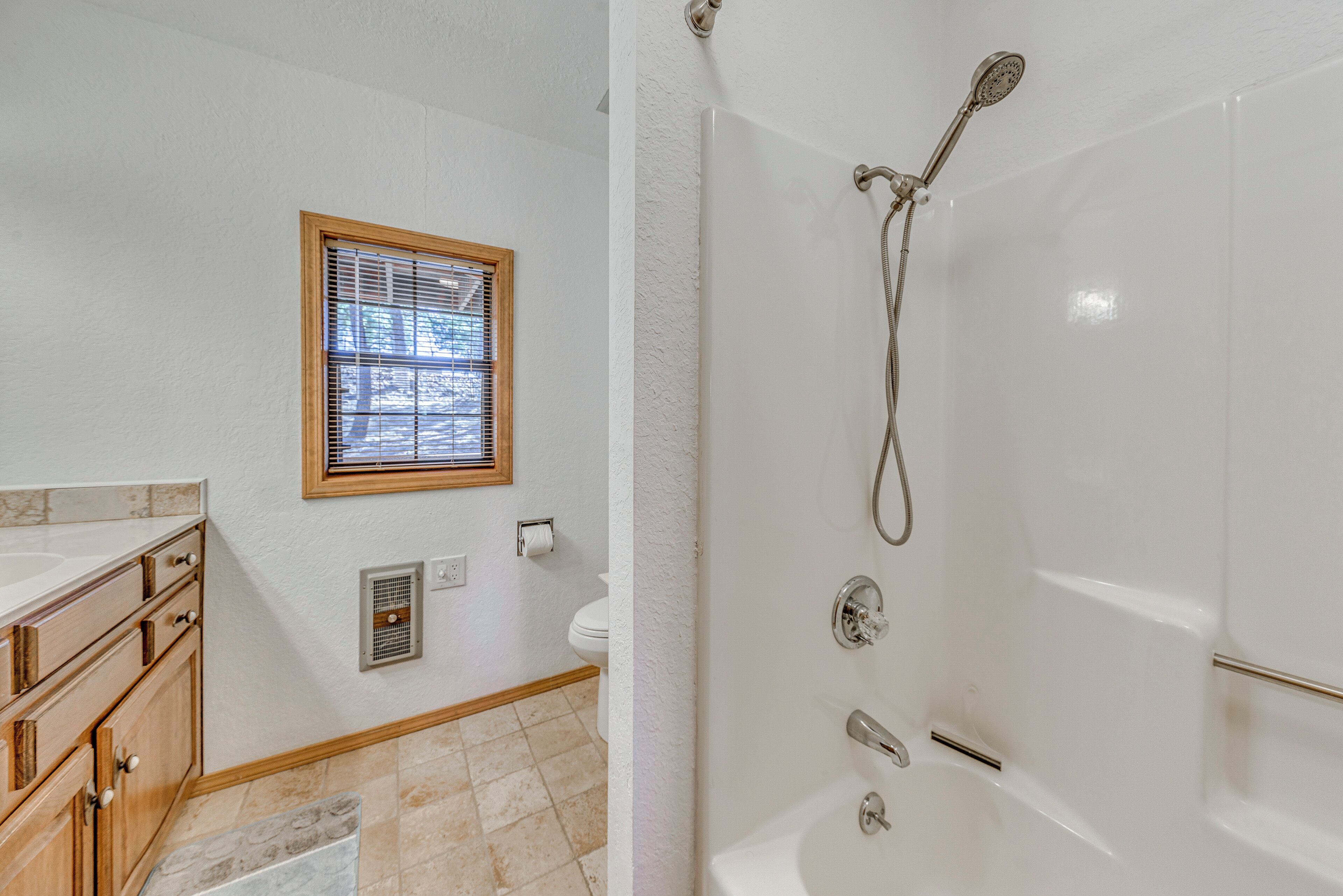 A bathroom with a shower, toilet, and vanity with drawers.