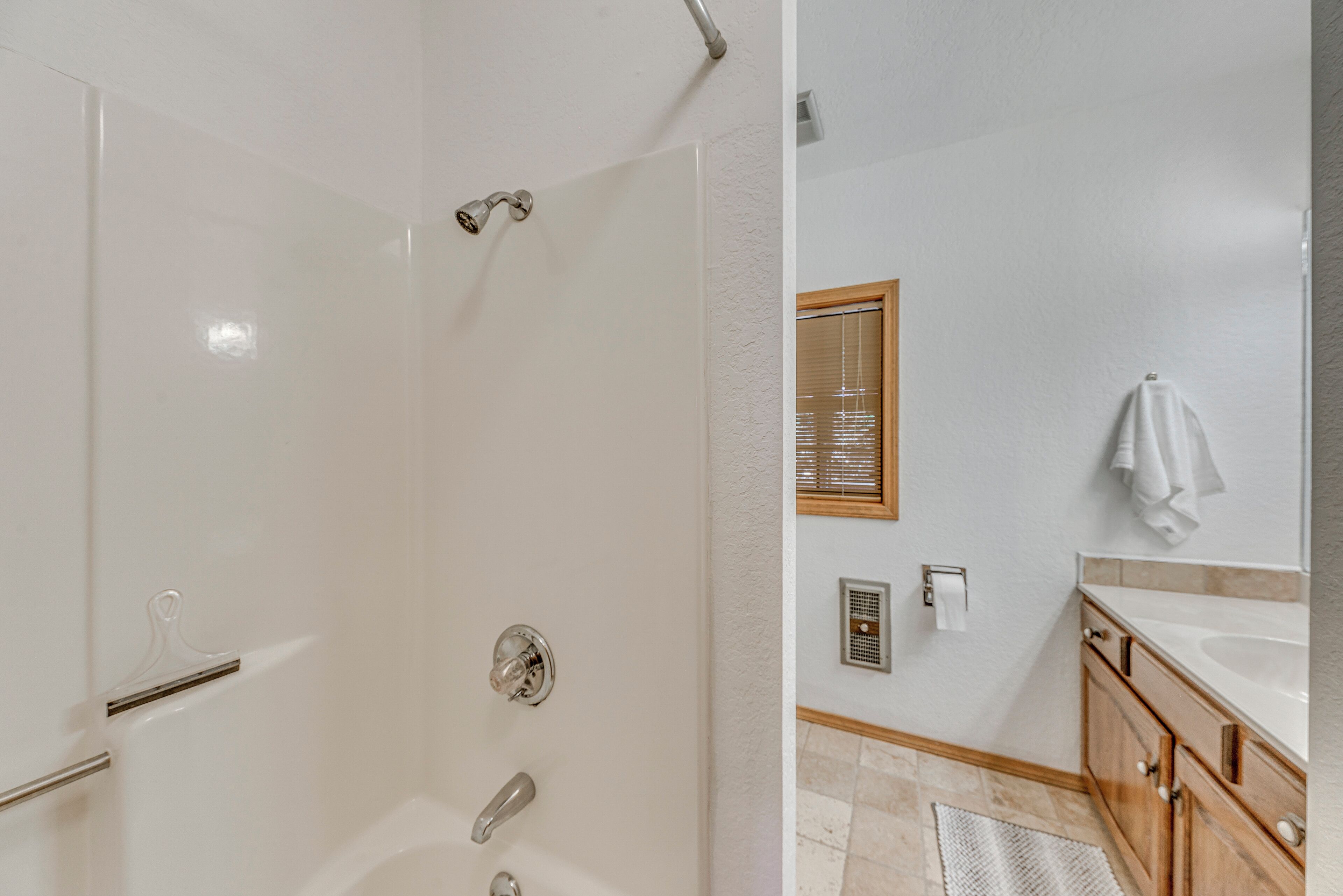 Un baño moderno con ducha, lavamanos y armarios de madera.