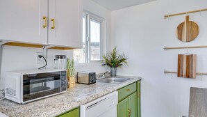Una cucina moderna con mobili bianchi, un piano di lavoro in granito, un forno a microonde, un tostapane e un lavandino.
