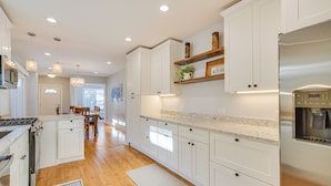 A modern kitchen with white cabinetry, a stainless steel refrigerator, and a granite countertop. - 2 Mi to Northwestern: Updated Home w/ Game Room! (Evanston)