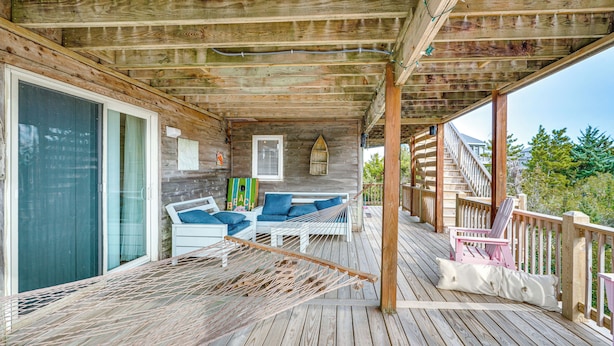A wooden deck with a hammock, a white sofa with blue cushions, and a pink chair. - Rooftop Deck & Hot Tub: Outer Banks Family Getaway (Salvo)