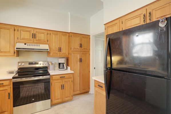 A kitchen with wooden cabinets, a stainless steel refrigerator, a built-in oven, and a coffee maker. - Porch Coffee, Square Nights & Rebel Saturdays (Oxford)