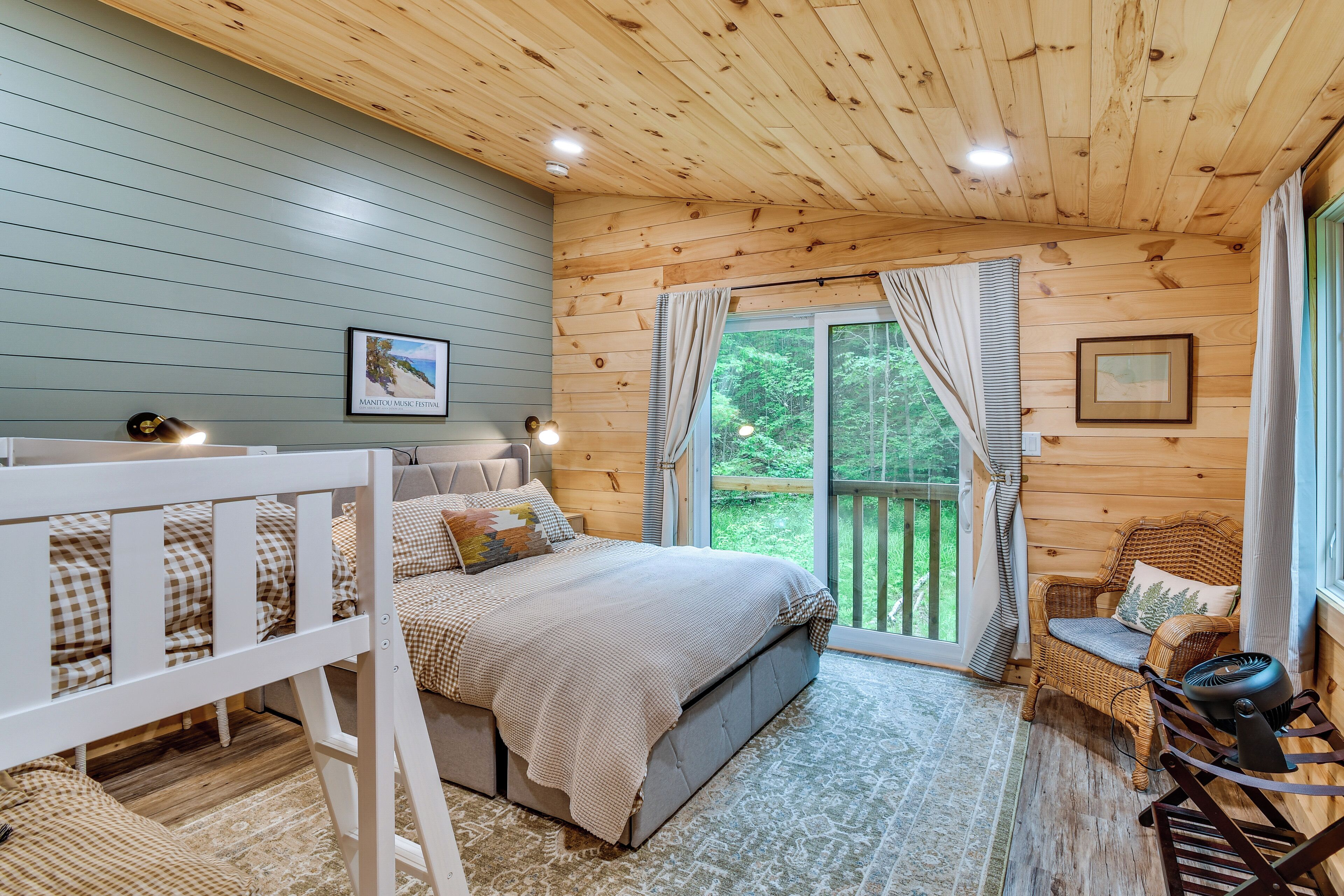 A cozy bedroom with a bunk bed, a large window, and a view of the outdoors.