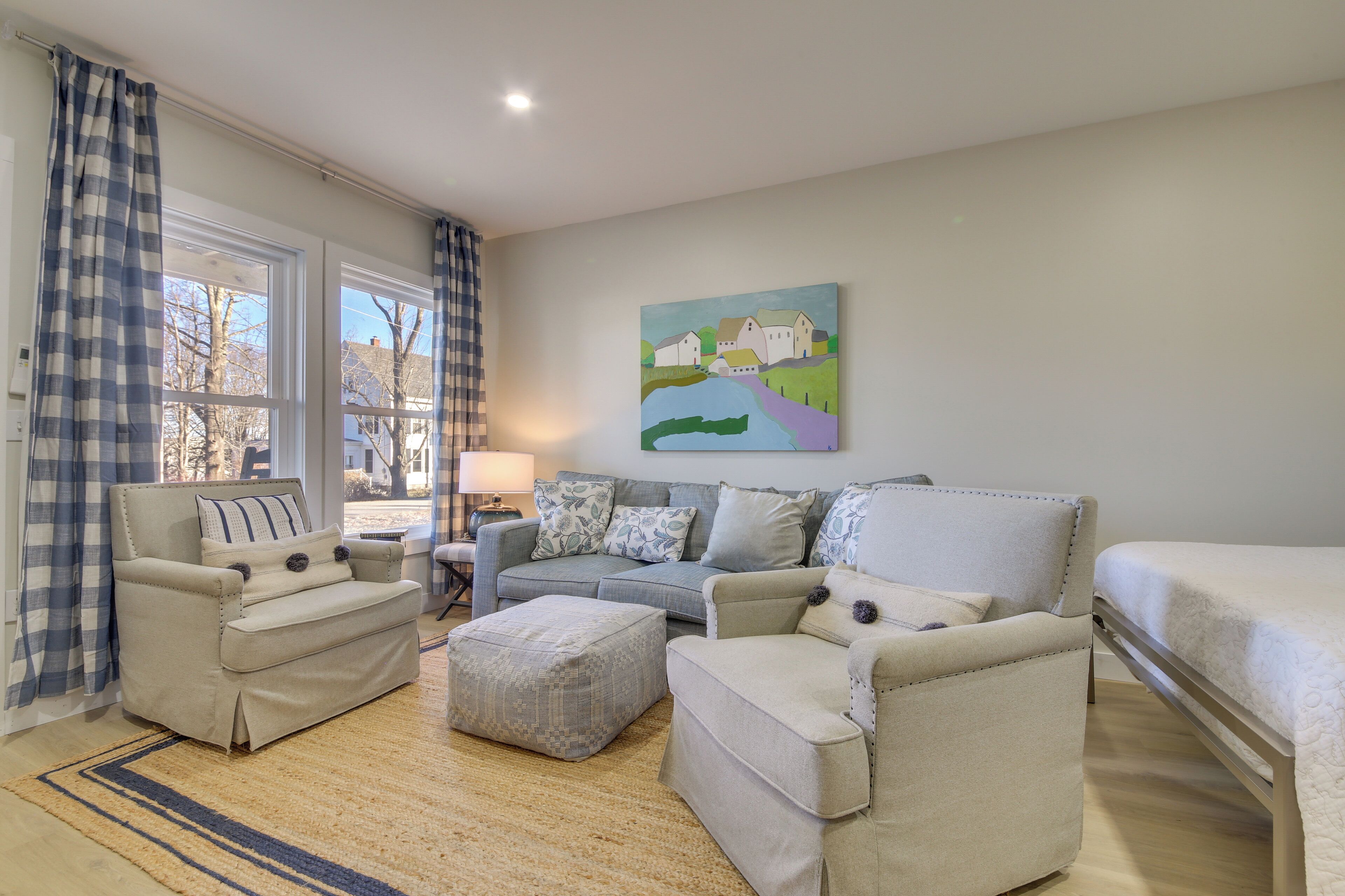 A living room with a sofa set, ottoman, and a painting on the wall.