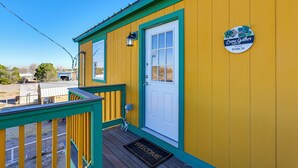 A yellow building with a green porch and a white door.