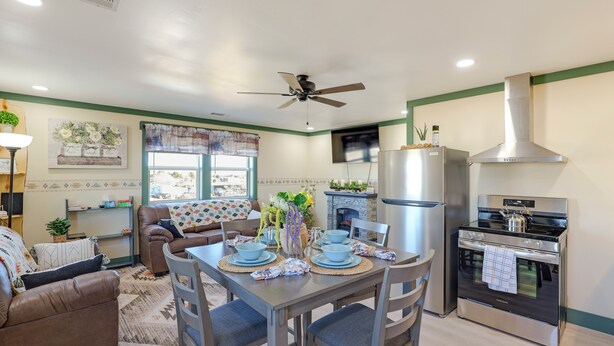 A modern kitchen with a dining area, including a table set for four, a sofa, and a ceiling fan.