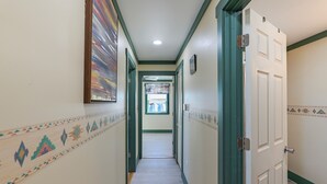 A hallway with patterned walls, a door on the right, and a window at the end.