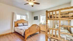 Een slaapkamer met een houten bed, een bureau en een stapelbed.