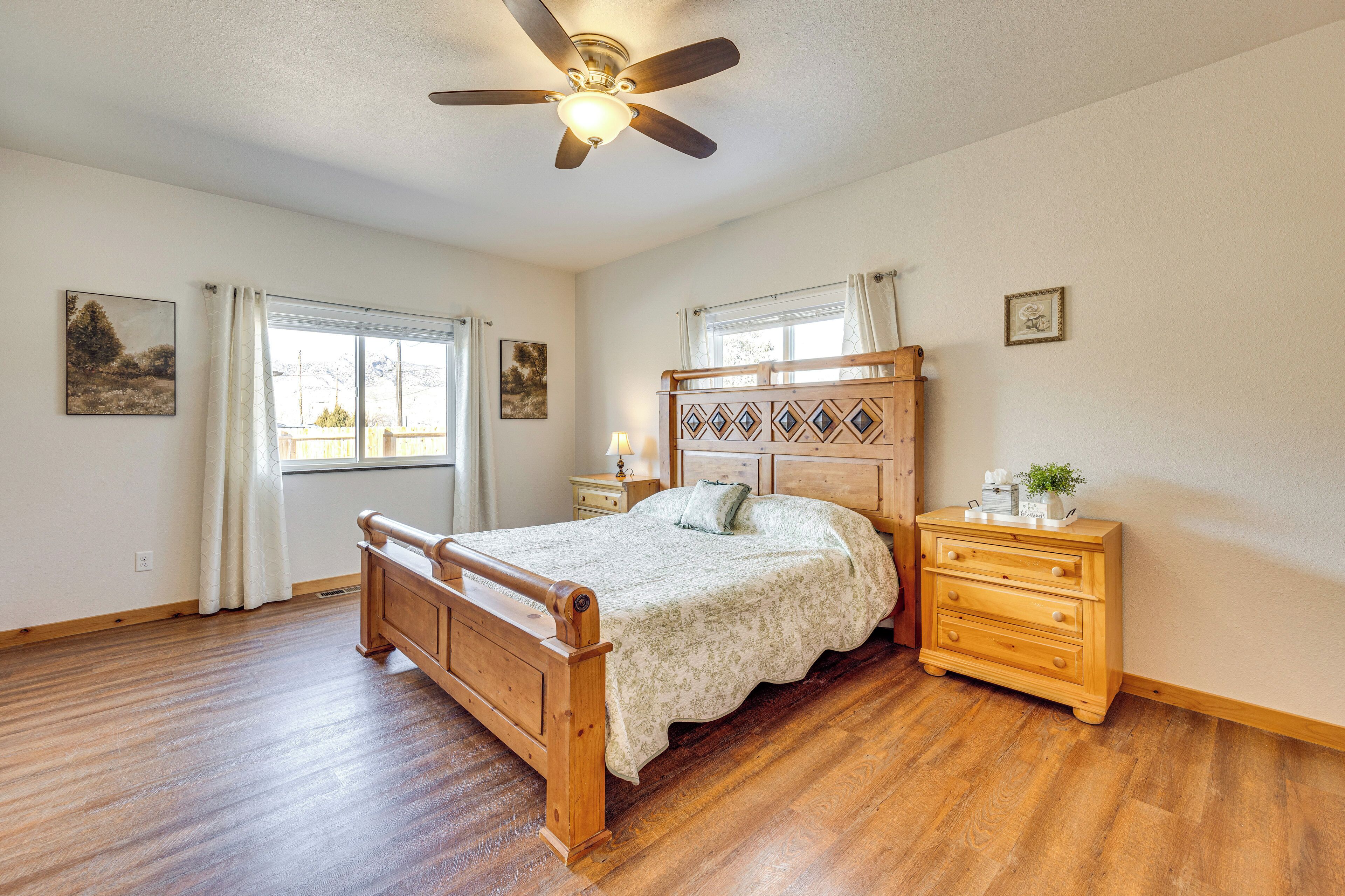 A bedroom with a wooden bed, a nightstand, a dresser, and a ceiling fan.