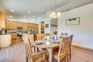 A spacious kitchen with wooden cabinets, a dining table set for four, and a chandelier.