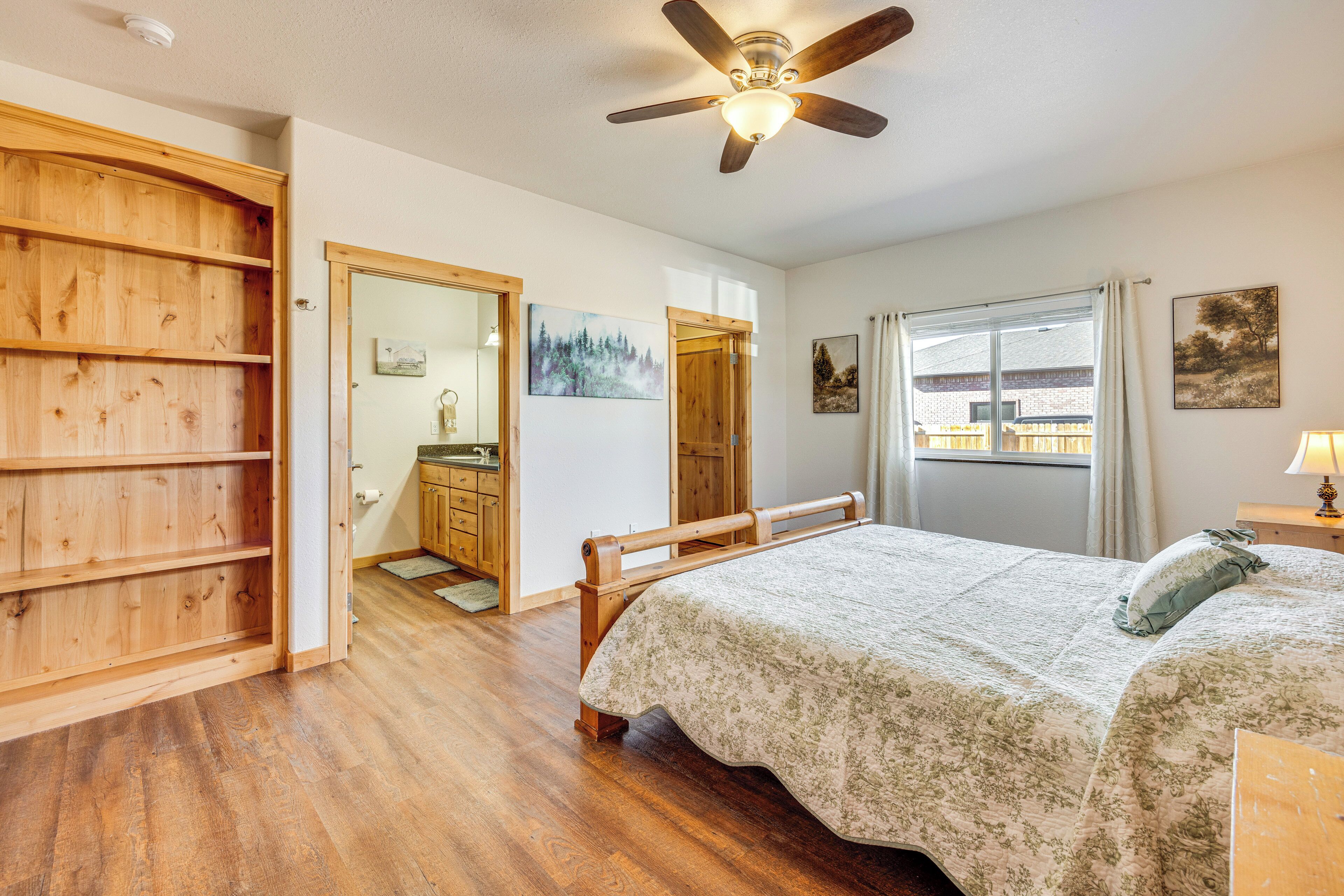 A bedroom with a wooden bed, a ceiling fan, a window with curtains, and a wooden wardrobe.