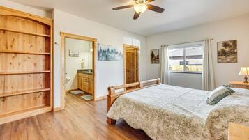 A bedroom with a wooden bed, a ceiling fan, a window with curtains, and a wooden wardrobe.