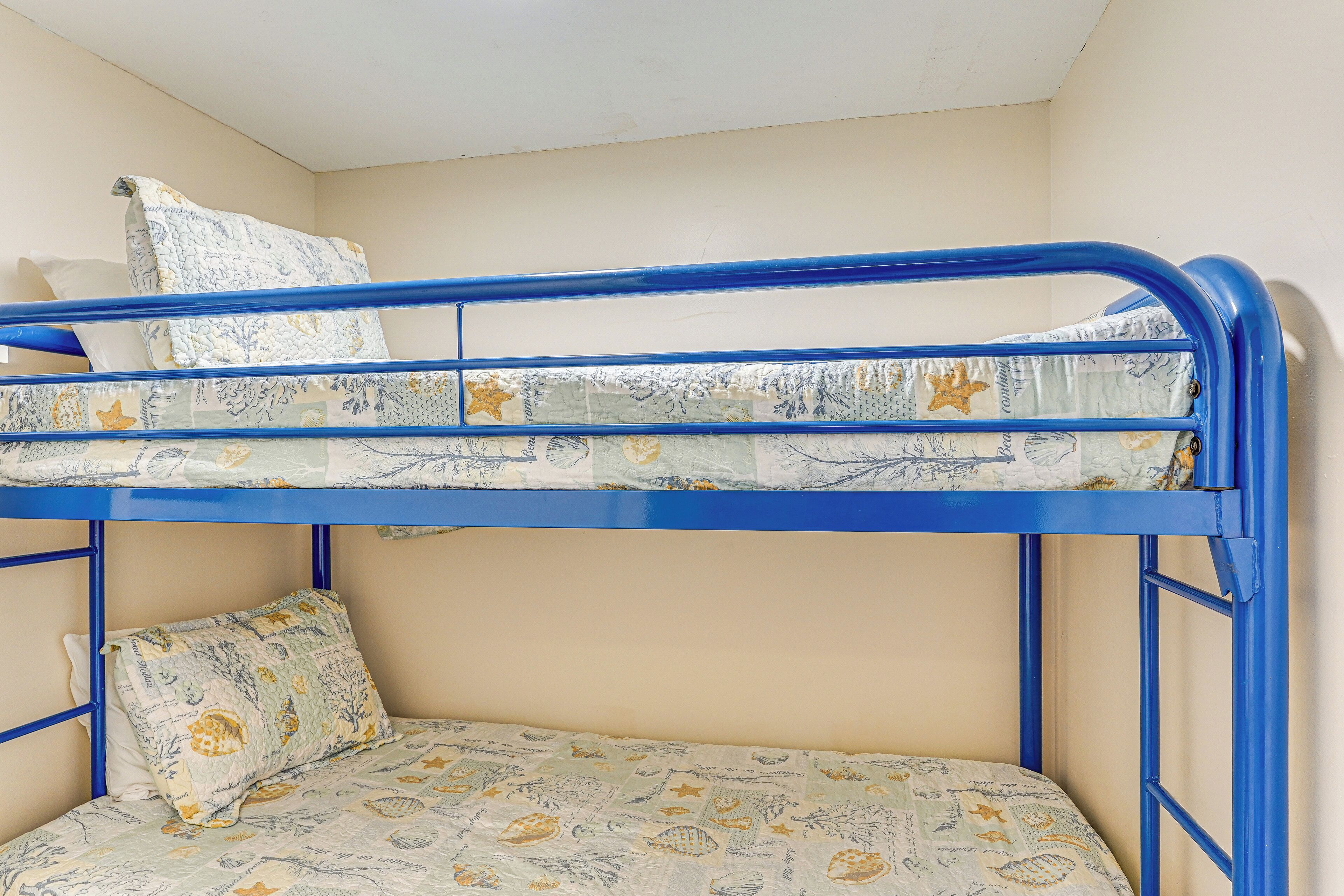 Ein Stockbett mit blauer Rahmung und gemusterten Betttextilien.