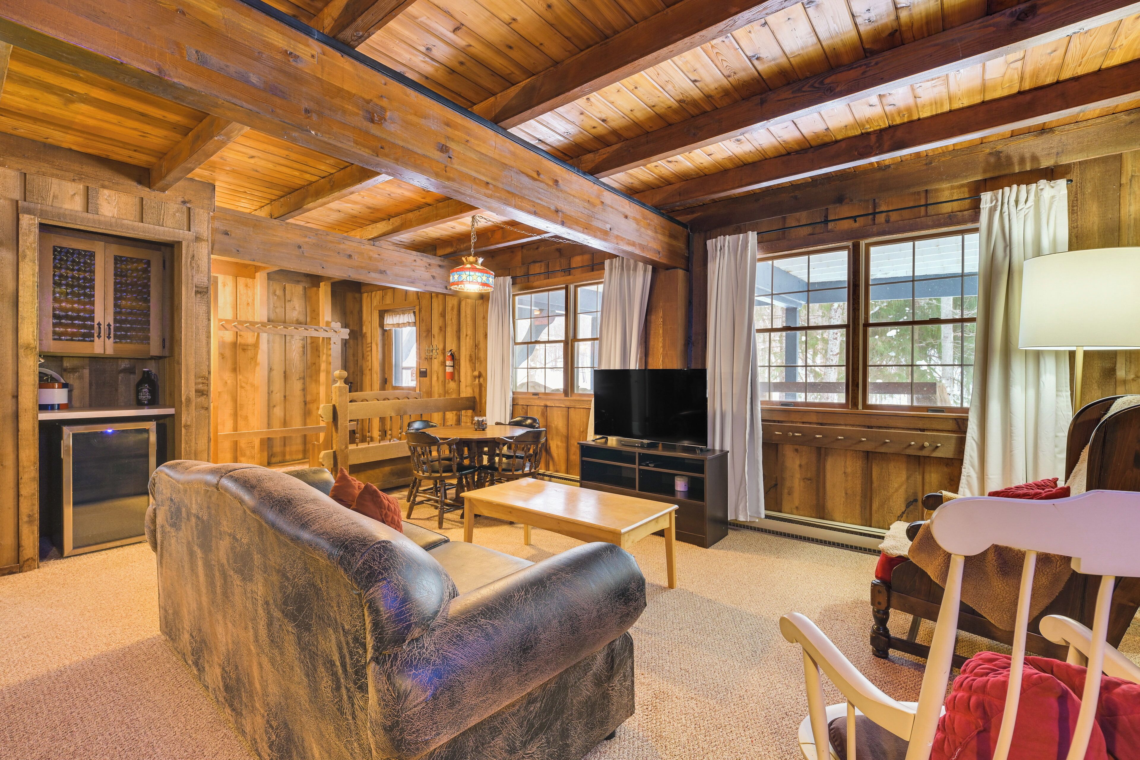 A cozy log cabin interior with a sofa, TV, dining table, and wooden walls.