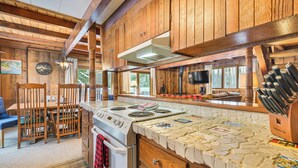 A rustic kitchen with wooden cabinets, a stone countertop, and a stove. - 2 Mi to Schuss Mountain: Cozy Cabin w/ Deck (Bellaire)