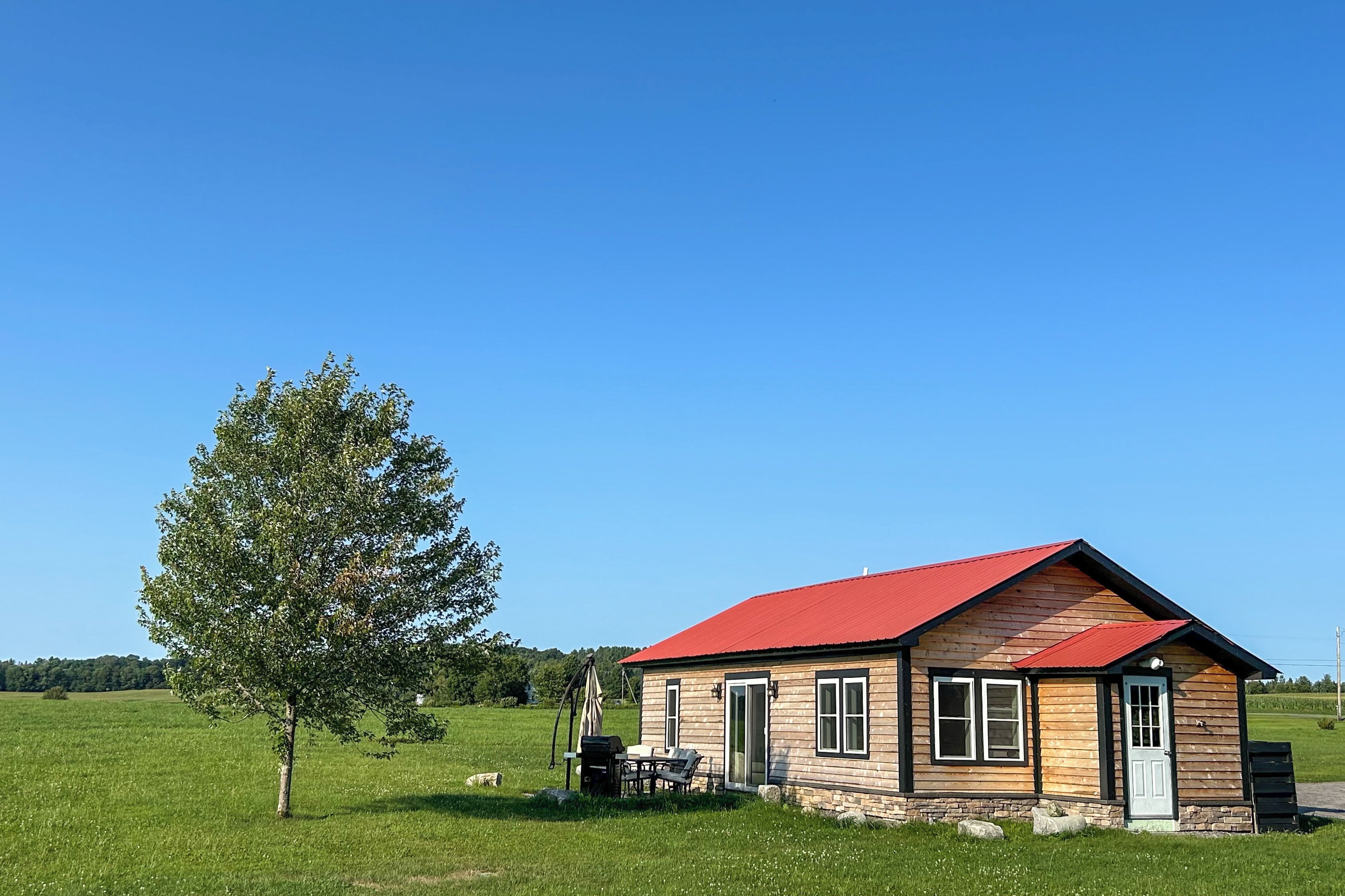 A small wooden cabin with a red roof, a stone foundation, and a single door.
