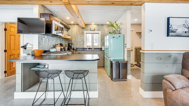 A modern kitchen with a central island, bar stools, a refrigerator, and a potted plant. - Ride From Your Door: Cabin w/ Vast Trail Access! (Hardwick)