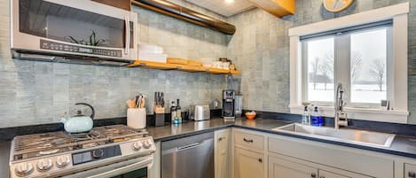 A modern kitchen with stainless steel appliances, a dishwasher, and a window with a view.