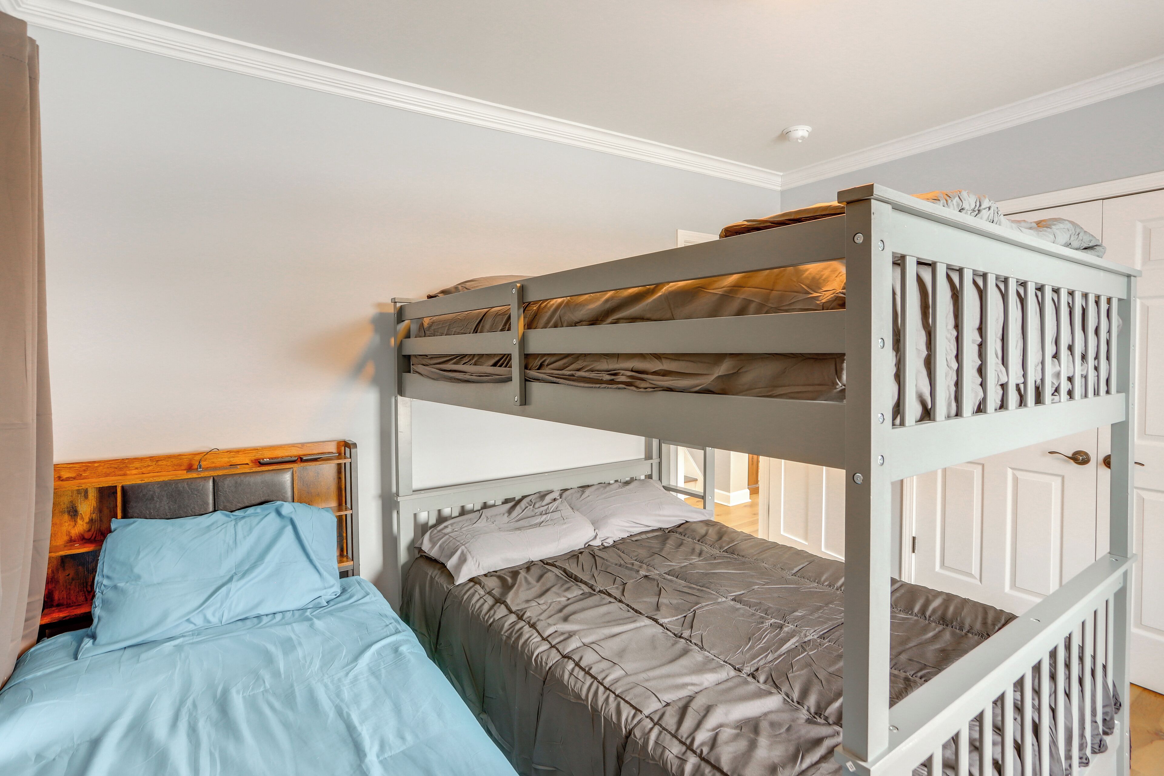 A bunk bed with a wooden headboard, a lower single bed, and a white door in the background.