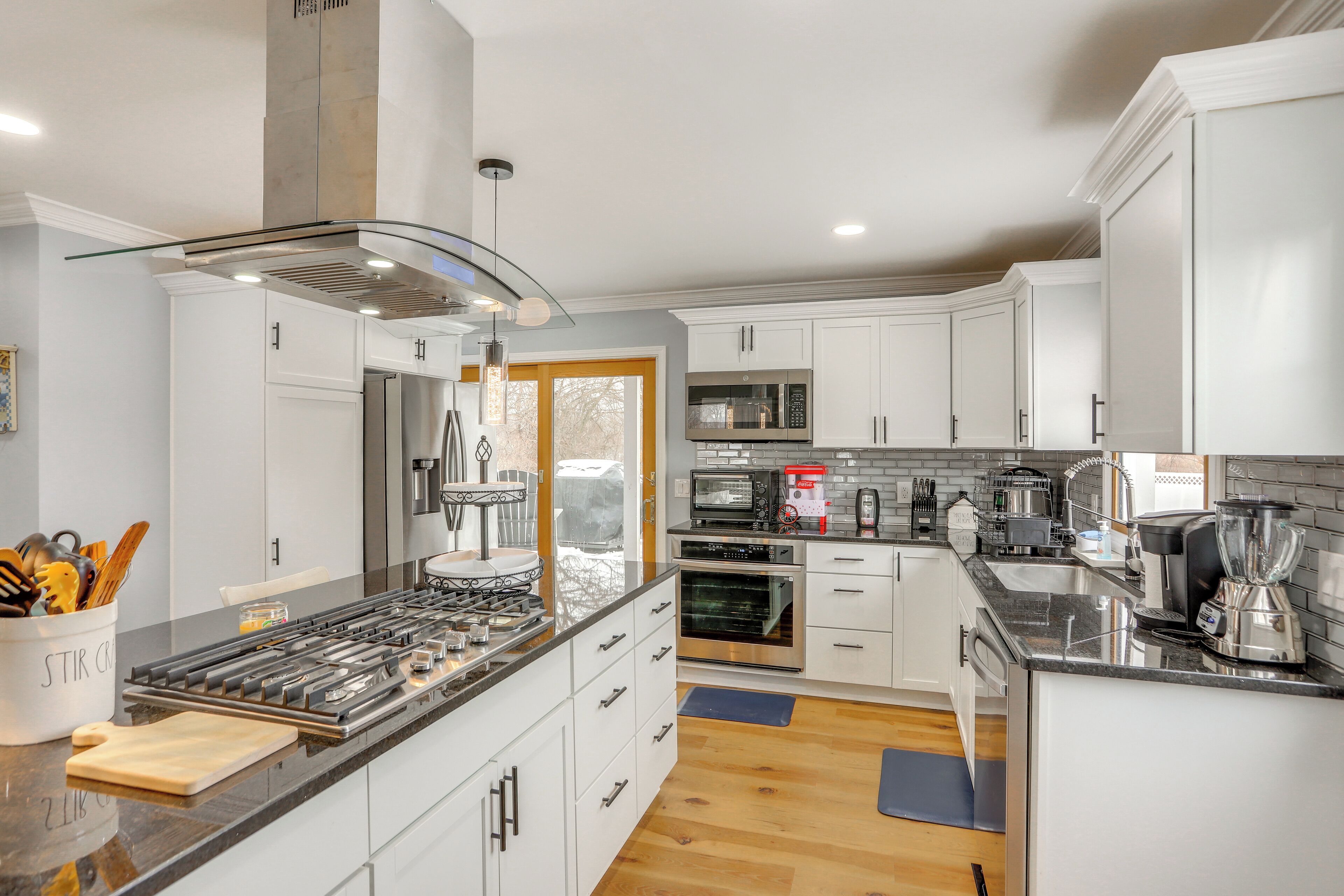 A modern kitchen with white cabinets, stainless steel appliances, and a glass backsplash.