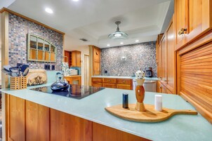 Una cocina con armarios de madera, encimera azul y salpicadero con mosaicos.