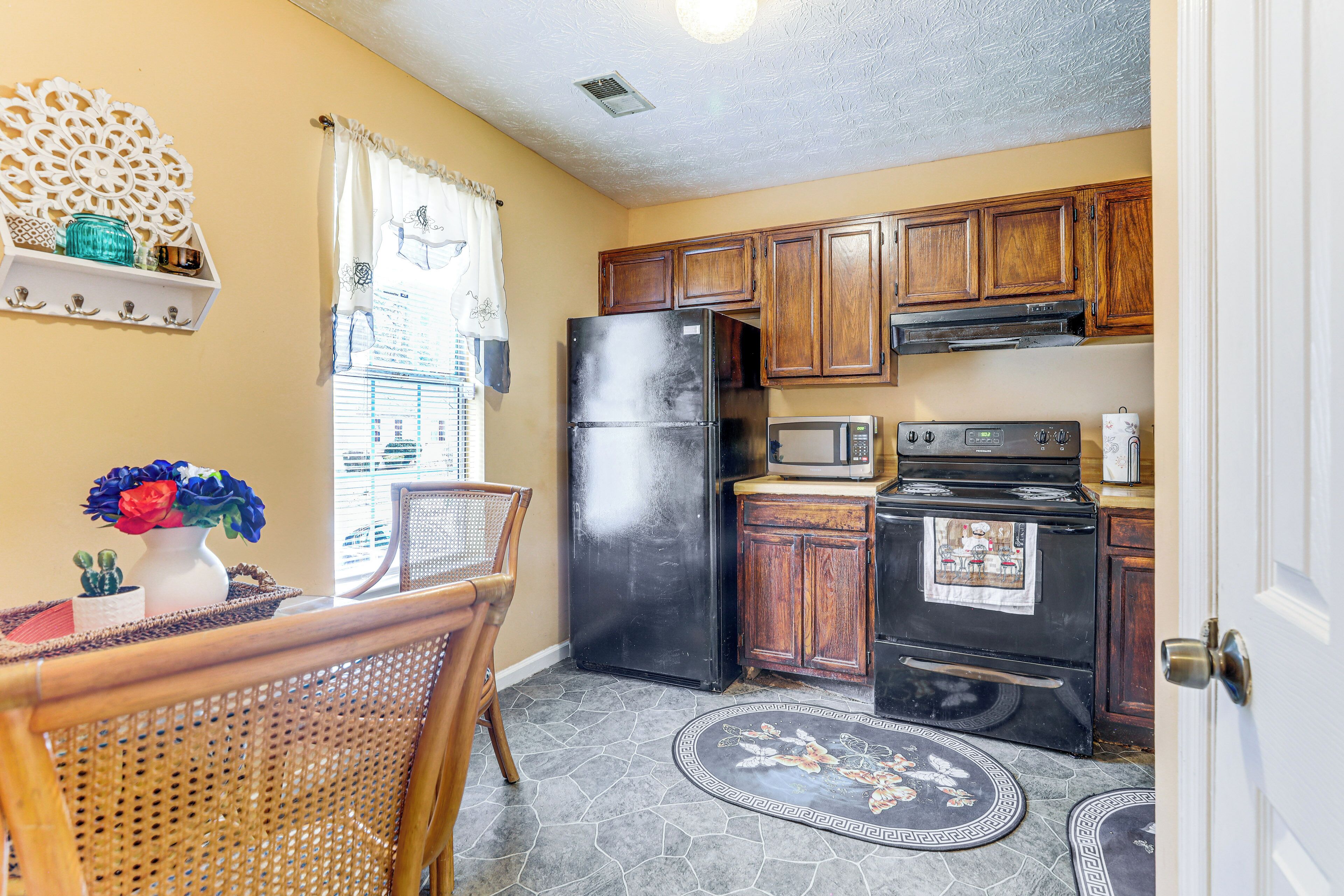 A kitchen with wooden cabinets, a refrigerator, a microwave, and an oven.