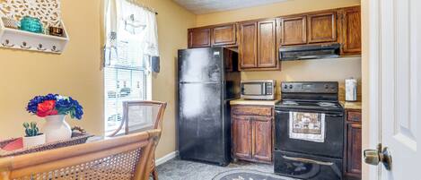 A kitchen with wooden cabinets, a refrigerator, a microwave, and an oven.