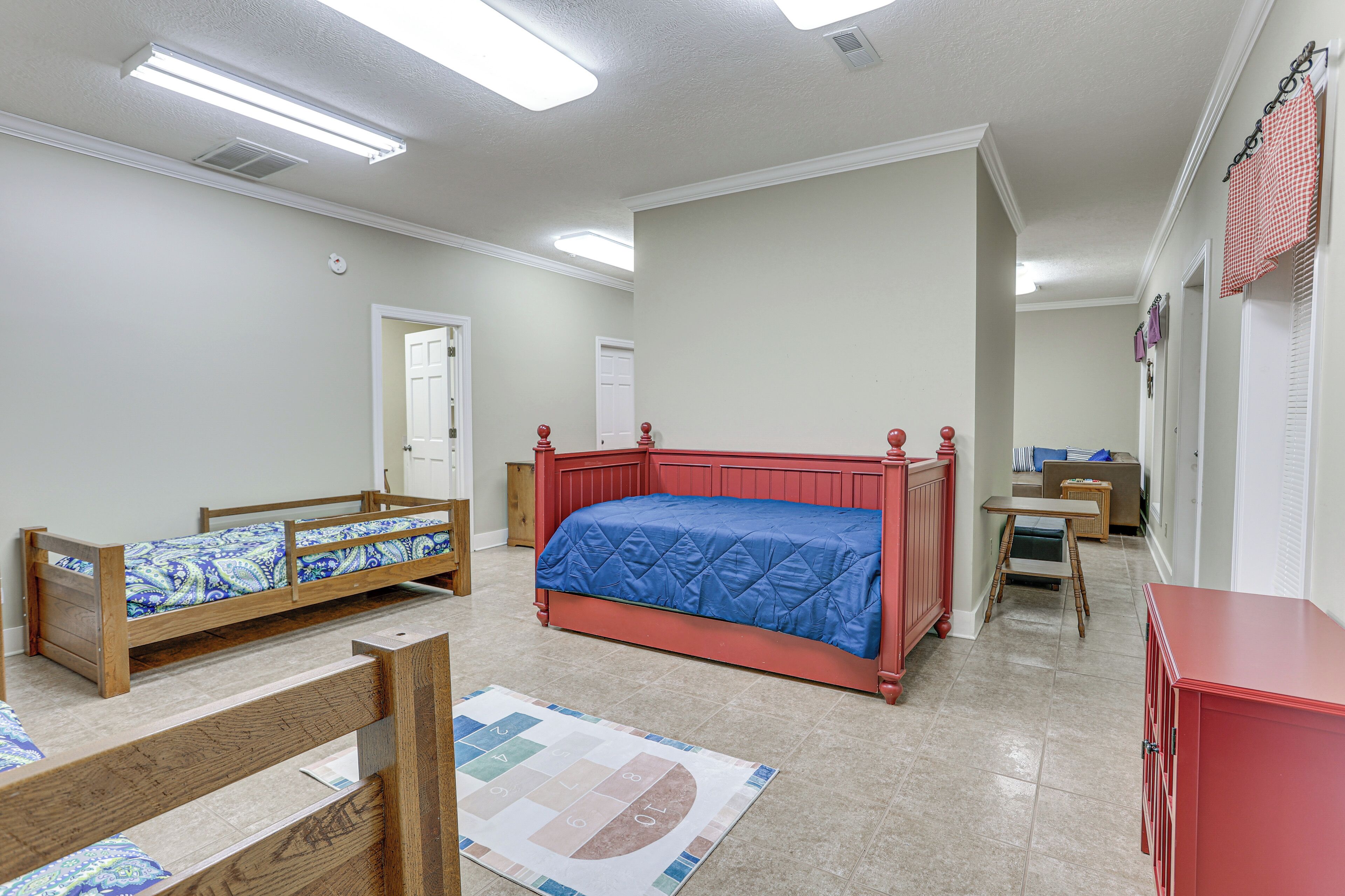A bedroom with a large bed, two smaller beds, a desk, and a wardrobe.
