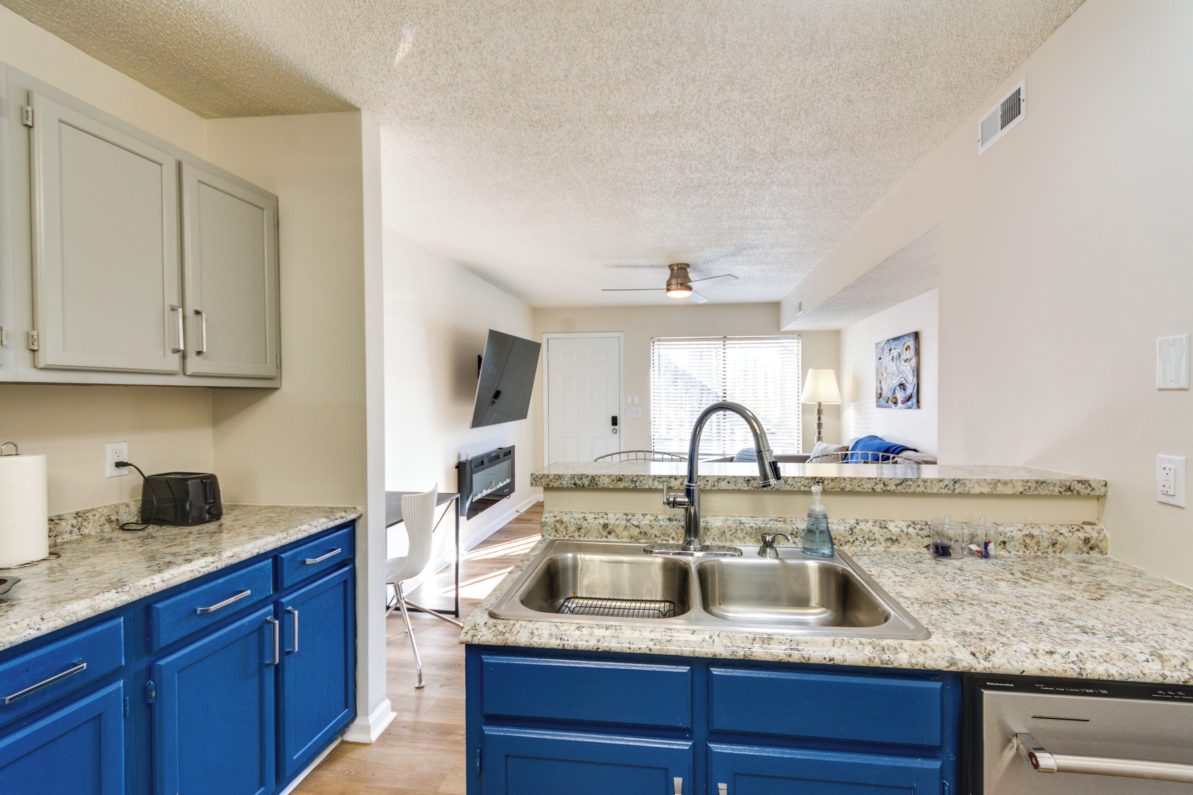 A kitchen with blue cabinets, a double sink, and a granite countertop.