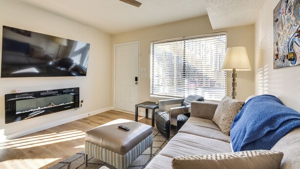 A living room with a flat-screen TV mounted on the wall, a ceiling fan, a sofa, a coffee table, and a window with blinds. - 15 Mi to Greensboro: Archdale Condo w/ Fireplace (High Point)