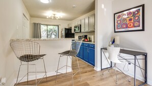 A modern kitchen with two bar stools, a dining table, and a microwave. - 15 Mi to Greensboro: Archdale Condo w/ Fireplace (High Point)