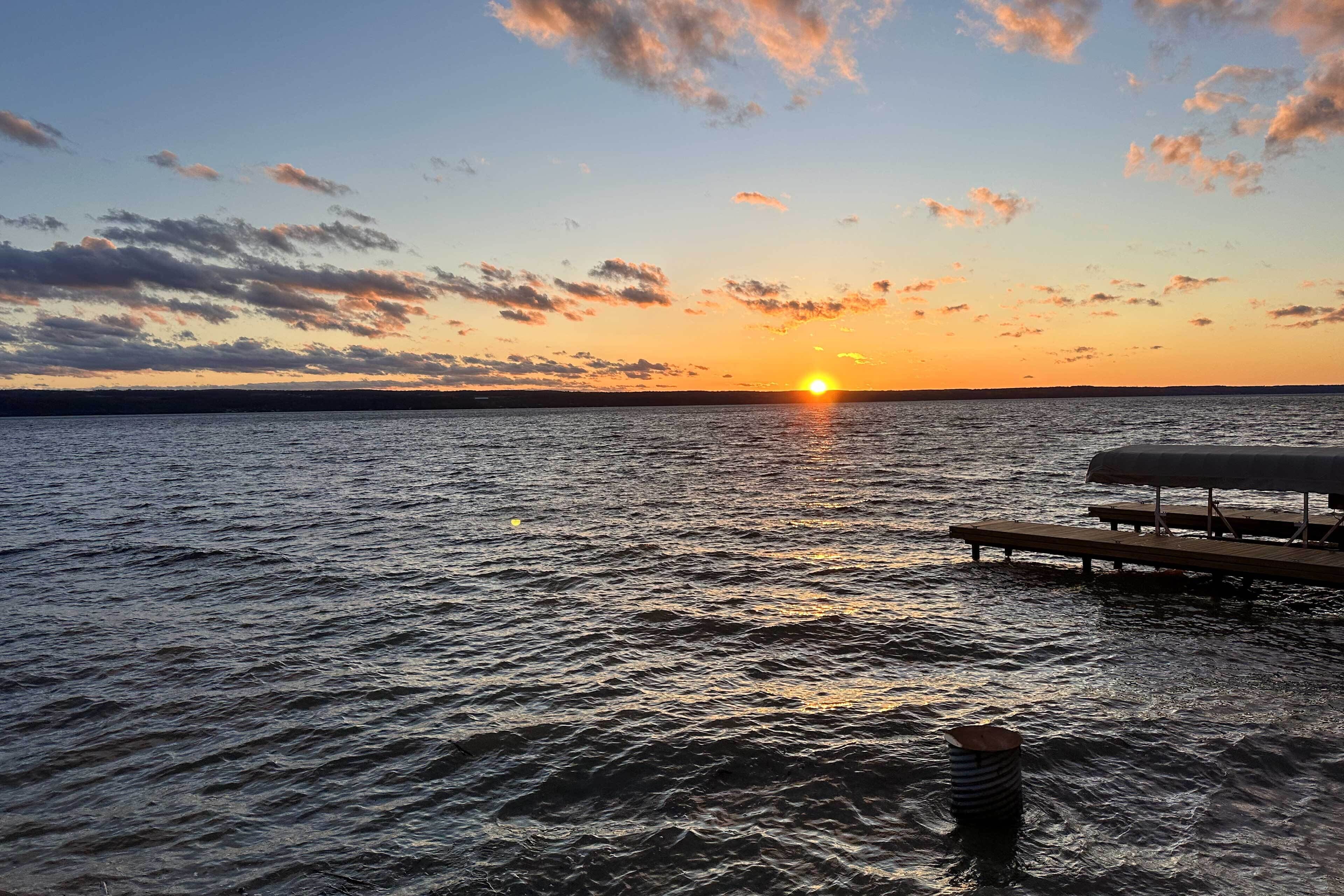 A sunset over a body of water with a dock and a floating structure.