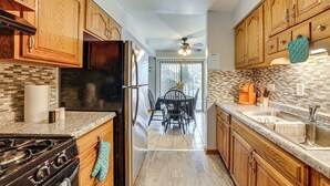 A kitchen with wooden cabinets, a black refrigerator, a stove, and a ceiling fan. - 3 Mi to Credit Union 1 Amphitheatre: Suburban Stay (Country Club Hills)