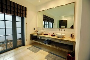 Features a spacious vanity with dual sinks and a shelf for storage.