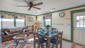 A living room with a brown leather couch, a wooden dining table with blue bowls, and a ceiling fan. - 9 Mi to Lake Carlsbad: Pet-friendly Apt (Carlsbad)