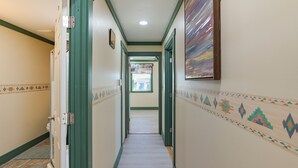 A hallway with green trim, patterned walls, and a door leading to a bathroom. - 9 Mi to Lake Carlsbad: Pet-friendly Apt (Carlsbad)