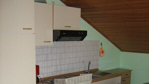 A compact kitchen with white cabinets, a black oven, and a wooden countertop. - Comfortably furnished vacation apartment with panoramic views (Arnbruck)