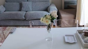 A room with a grey sofa, a white table with a vase of flowers, and a mirror on the wall. - APARTMENT MILAN CENTER PENTHOUSE - PORTA VENEZIA 2DX (Milano)