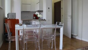A modern kitchen with white cabinets, a dining table with clear chairs, and a red appliance. - APARTMENT MILAN CENTER PENTHOUSE - PORTA VENEZIA 2DX (Milano)