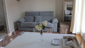 A living room with a grey sofa, a coffee table with a vase of flowers, and a small table with a tray. - APARTMENT MILAN CENTER PENTHOUSE - PORTA VENEZIA 2DX (Milano)
