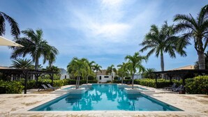 A rectangular swimming pool with clear blue water, surrounded by stone tiles and palm trees. - Indigo Garden at Blue Bay Golf Beach Resort (Sint Michiel)