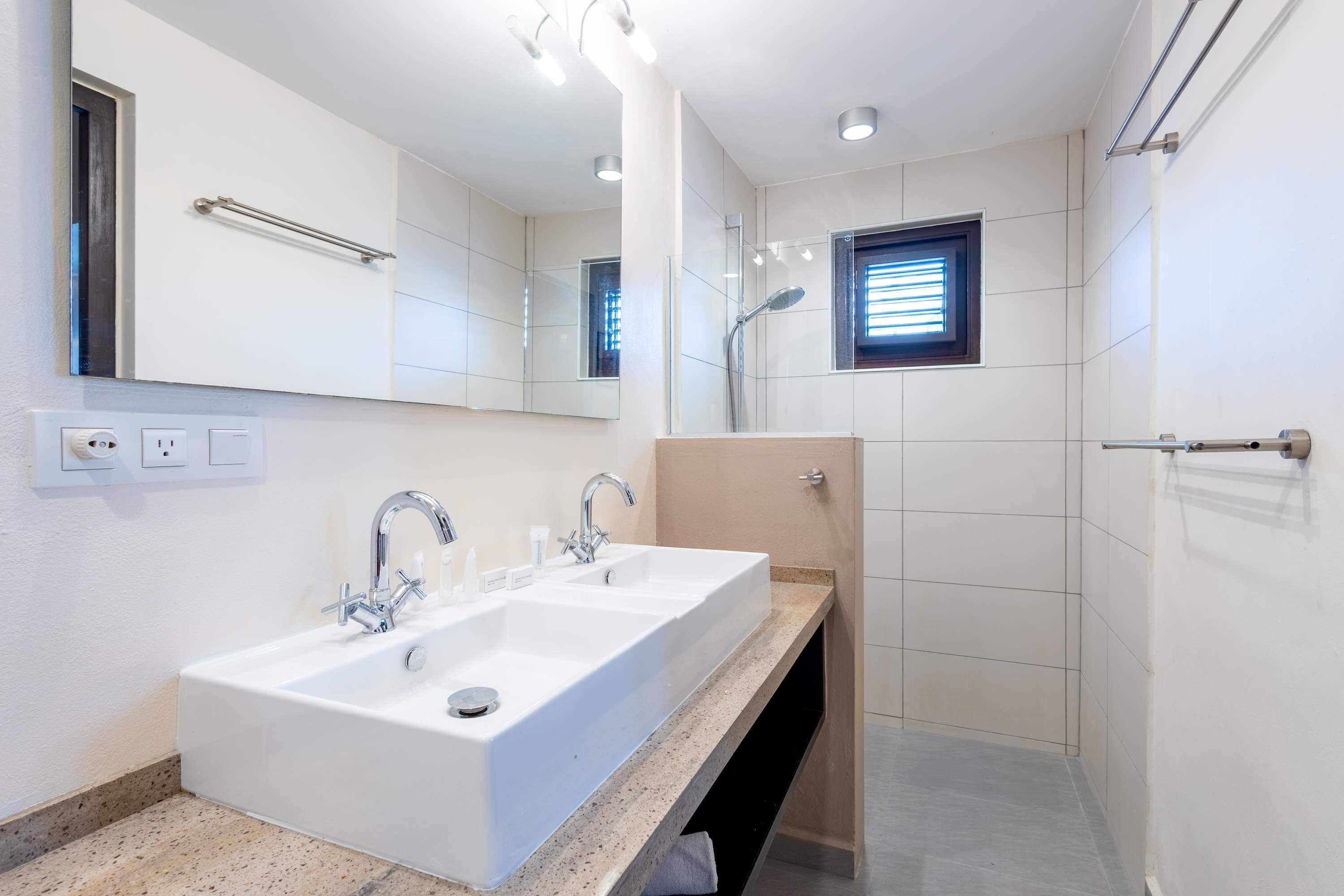 Een moderne badkamer met een dubbele wastafel, een spiegel en een douche.