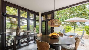 A dining area with a round table, wicker chairs, and a wicker pendant light. - Indigo Garden at Blue Bay Golf Beach Resort (Sint Michiel)