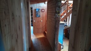 Interior de madera con una escalera, paredes de madera y un objeto azul en la pared.