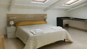 Ein Schlafzimmer mit Bett, Schreibtisch und Dachfenstern.