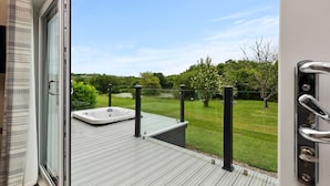 A deck with a hot tub and a view of a grassy area with trees. - Mallard s Rest - Countryside Hot Tub (Narberth)